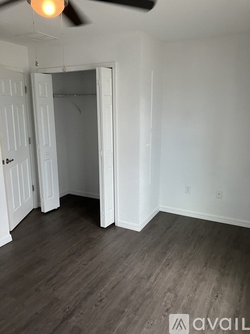 A room with a ceiling fan and a doorway leading to another room.