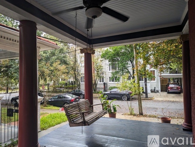 A wooden bench is on a porch with a ceiling fan.