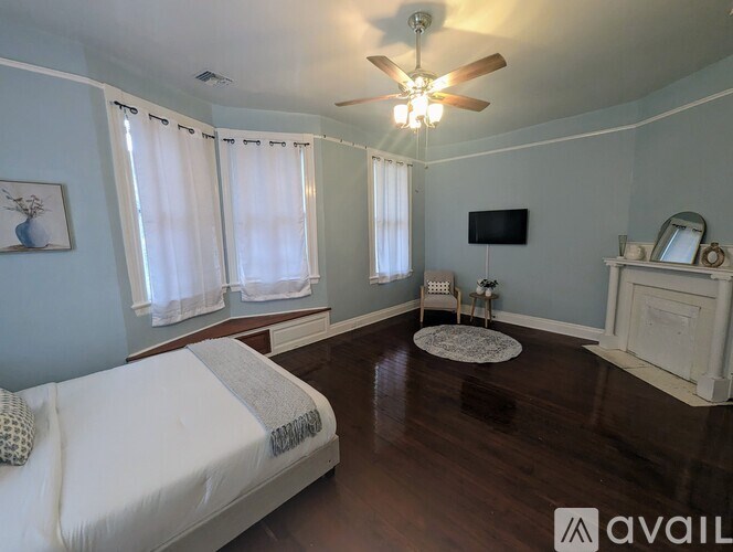 A bedroom with a bed, a chair, a TV, and a fireplace.