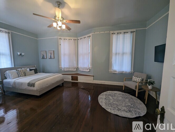 A bedroom with a bed, chair, and a ceiling fan.