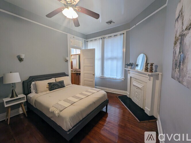 A bedroom with a bed, a lamp, a mirror, and a painting on the wall.