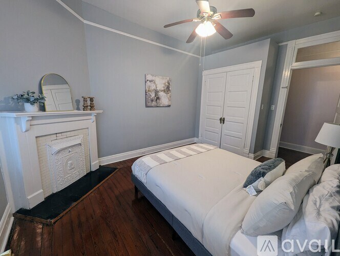 A bedroom with a bed, a fireplace, and a ceiling fan.