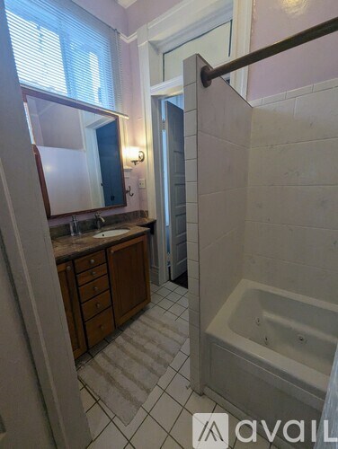 A bathroom with a tub, sink, and mirror.