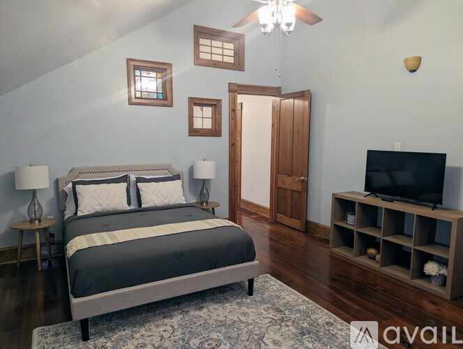 A bedroom with a large bed, a television, and a chandelier.
