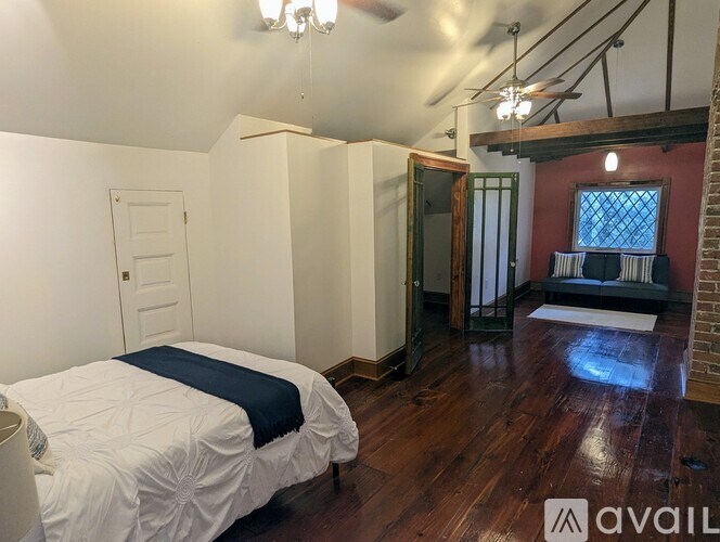 A bedroom with a bed, a window, and a wooden floor.