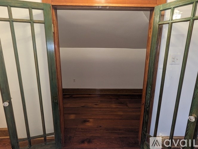 A room with wooden floors and green doors.