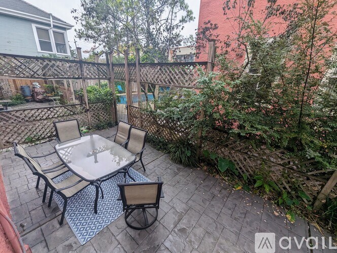 A patio with a table and chairs surrounded by a fence and bushes.