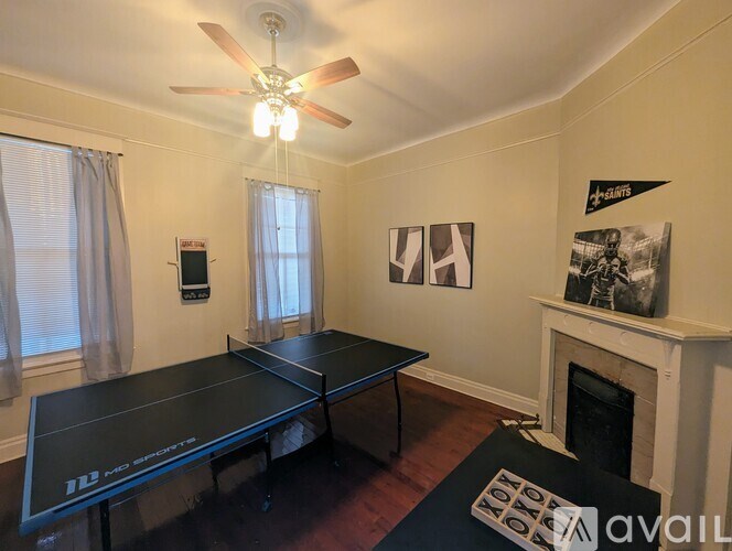 A ping pong table is in the middle of a room with a fireplace and pictures on the wall.