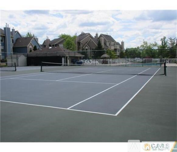 A tennis court with white lines on a grey surface.