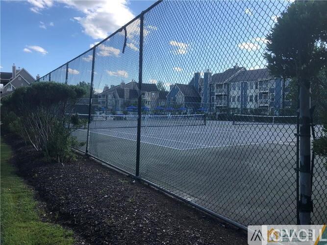 A chain link fence with a residential area in the background.