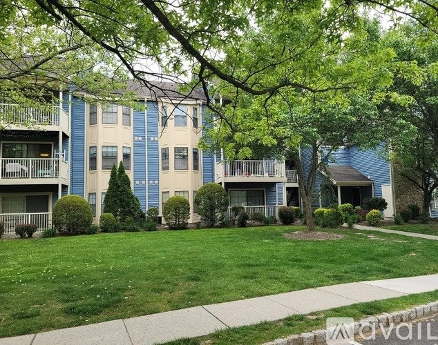 Apartment complex with green lawn and trees.