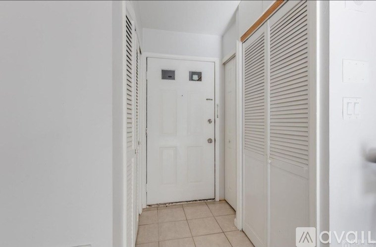 A white door with a black handle is in a hallway.