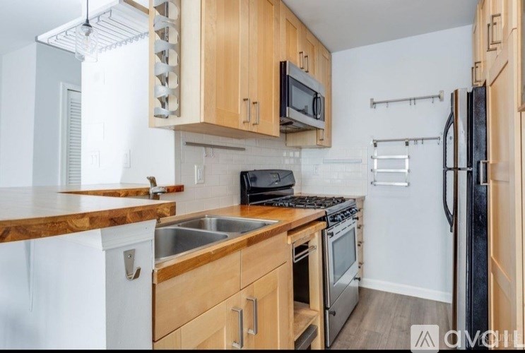 A kitchen with wooden cabinets and a black refrigerator.