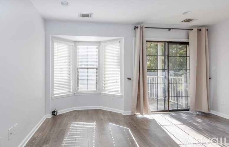 A room with a sliding glass door and a window with blinds.