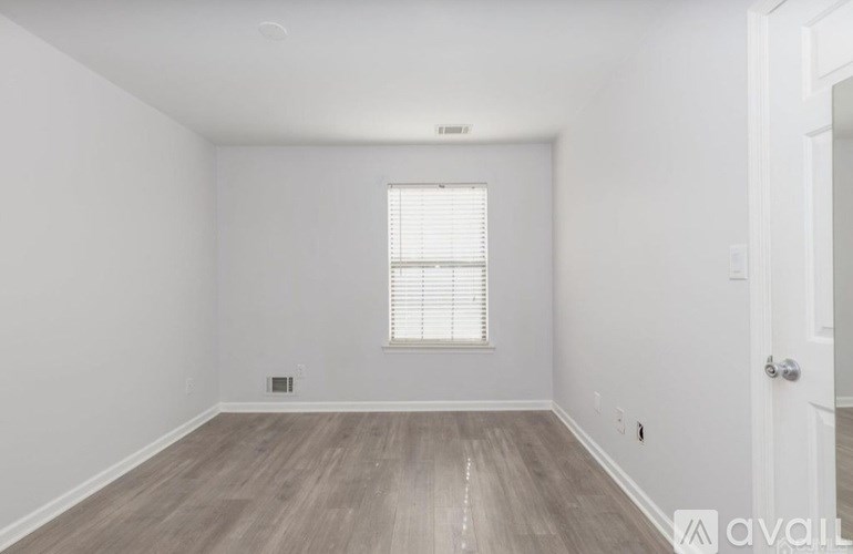 A room with wooden flooring and a window with blinds.