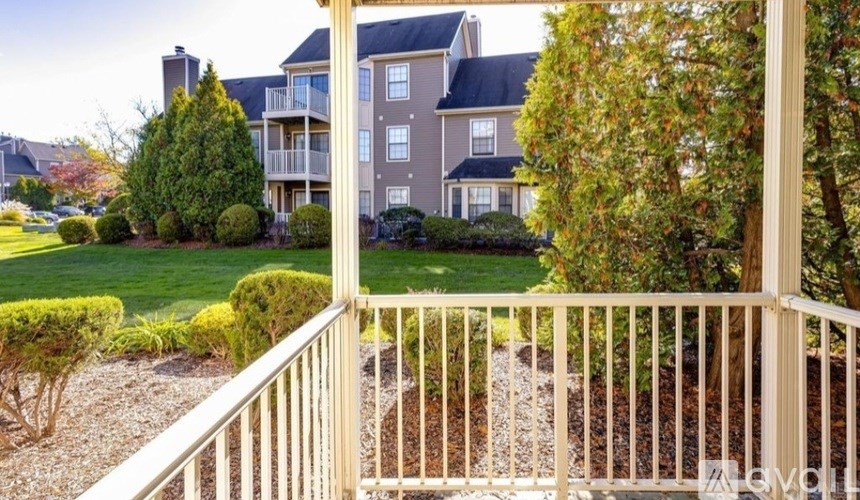 A view from a balcony overlooking a well-manicured lawn and apartment buildings.