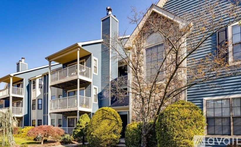 A blue building with a balcony and a tree in front.
