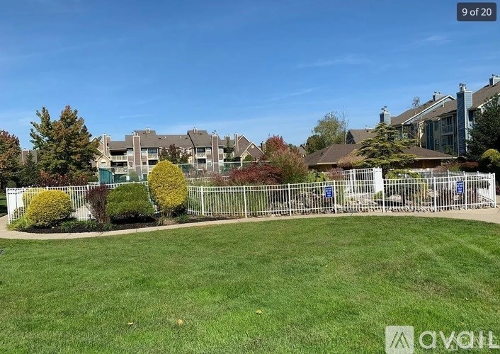 A grassy area with a fence and trees in the background.