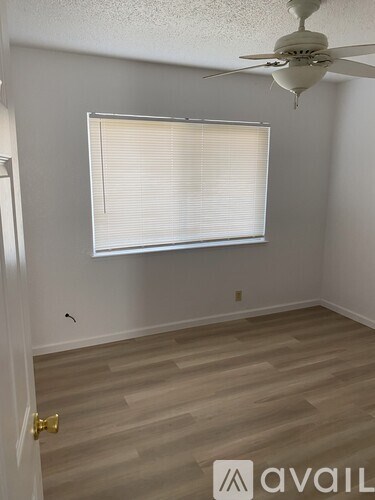 A room with a ceiling fan and a window with blinds.