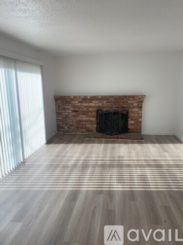 A room with a brick fireplace and wooden flooring.