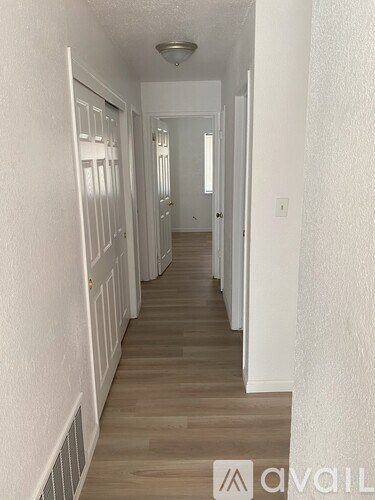 A long hallway with white walls and wood flooring.