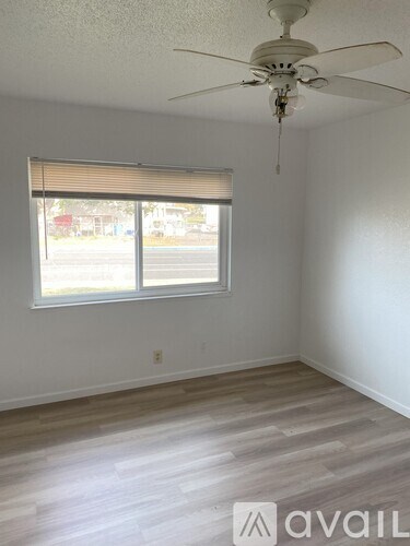A room with a ceiling fan and a window with blinds.
