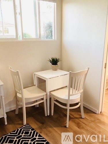 A white table with two chairs and a potted plant on it.