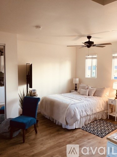 A bedroom with a bed, chair, and ceiling fan.