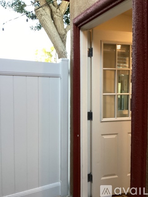 A white door with a black handle is open to a room with a window.
