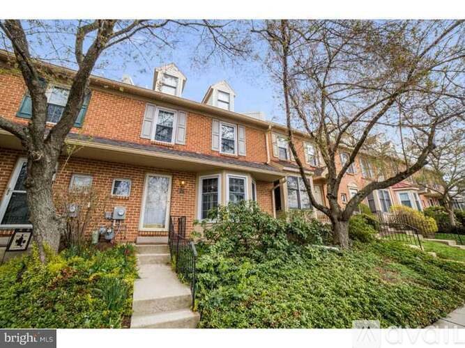 A red brick house with a black iron fence and a tree in front.