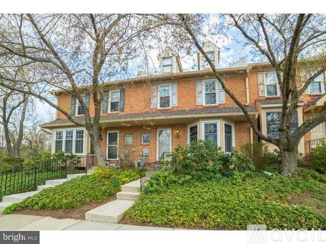 A red brick house with a black iron fence in front.