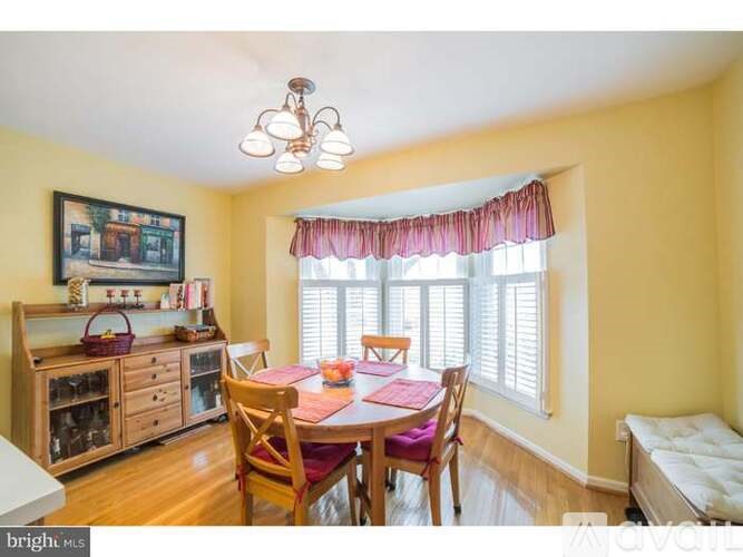 A dining room with a table set for four and a chandelier hanging from the ceiling.