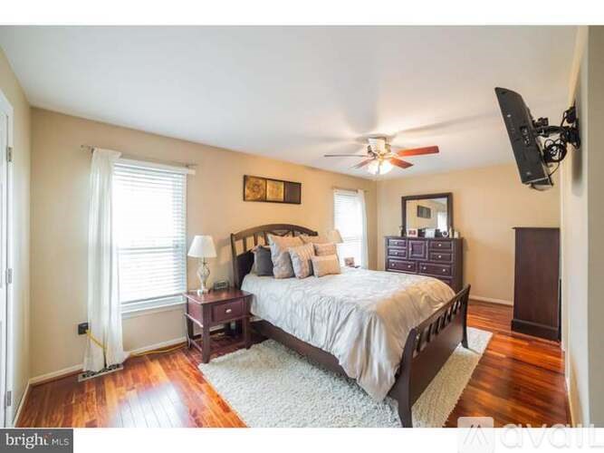 A bedroom with a bed, dresser, and ceiling fan.