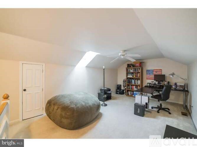 A room with a ceiling fan, a desk with a chair, and a bookshelf with an American flag.