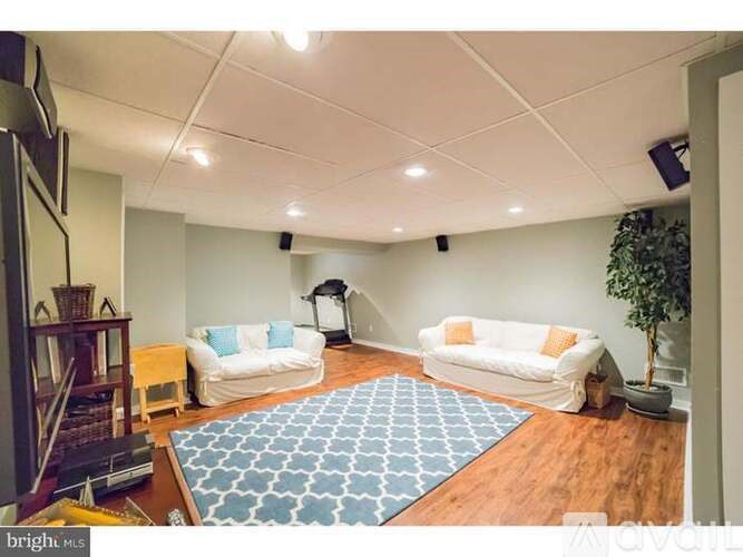A living room with a white couch and a blue rug.
