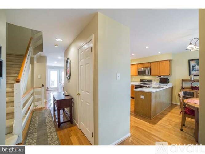 A bright and spacious home interior with a staircase on the left and a kitchen area on the right.