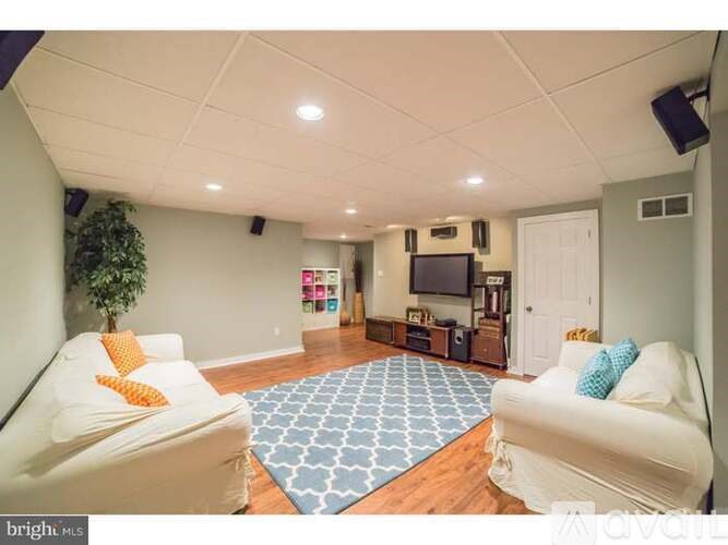 A living room with a white couch and a blue rug.