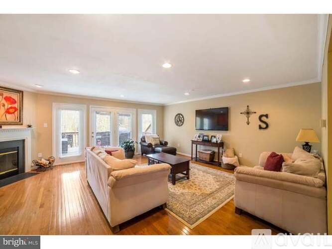 A living room with a fireplace and a flat screen TV mounted on the wall.