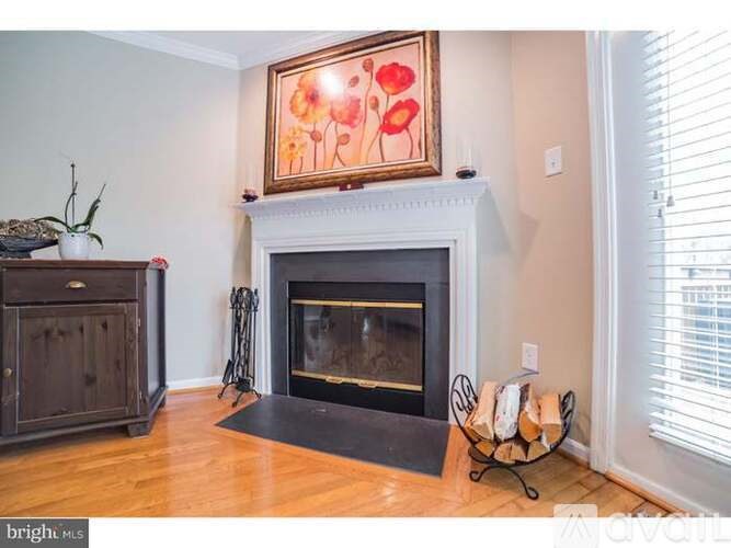 A fireplace with a painting above it and a vase on the mantle.