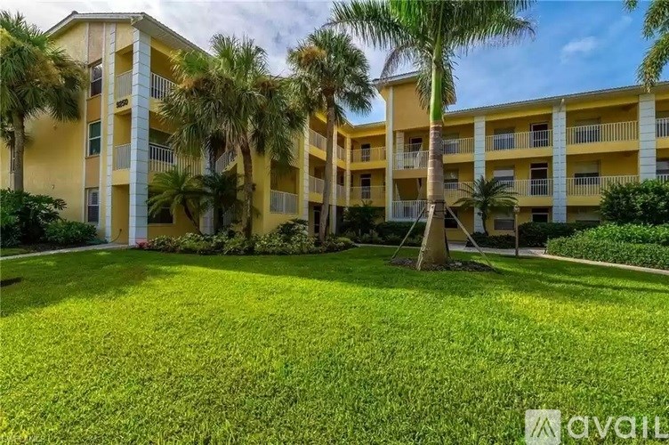 A sunny day at a yellow apartment complex with palm trees.