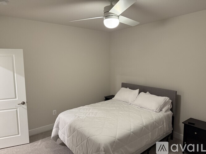 A bedroom with a bed, nightstand, and ceiling fan.