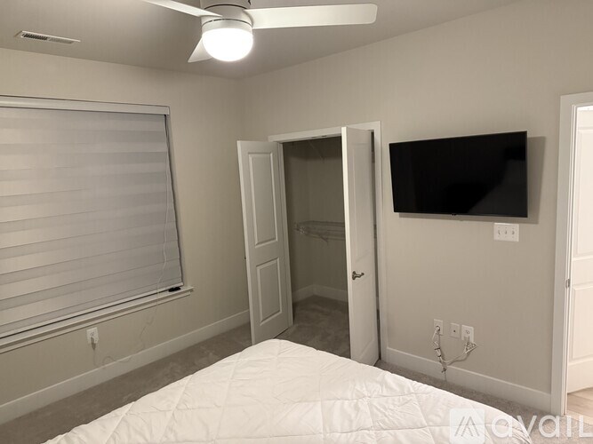 A bedroom with a bed, a ceiling fan, and a television.