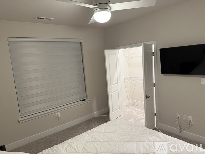 A bedroom with a bed, a ceiling fan, and a window with blinds.