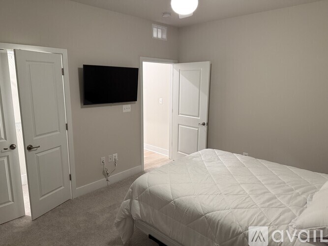 A bedroom with a bed, a television, and two doors.