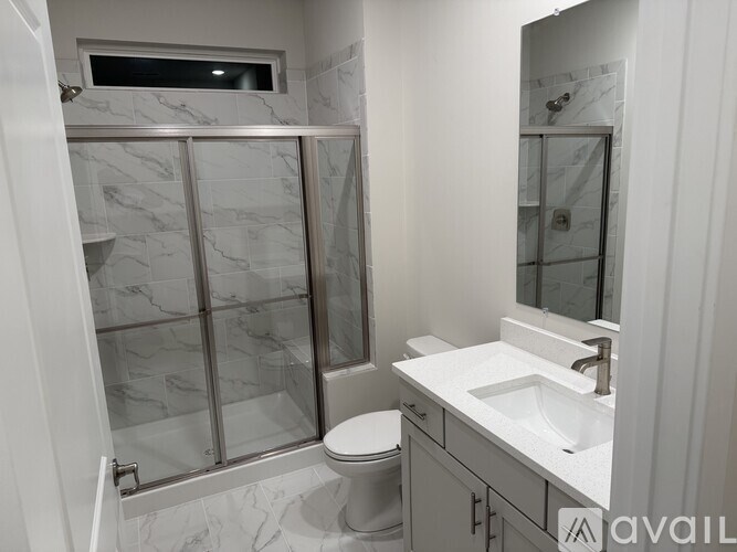 A bathroom with a marble tile shower and a white toilet.