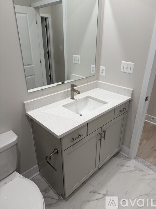 A bathroom with a sink, toilet and a mirror.