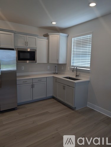 A kitchen with wooden floors and white cabinets.