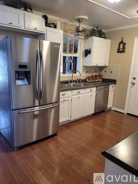 A kitchen with a stainless steel refrigerator and wooden floors.