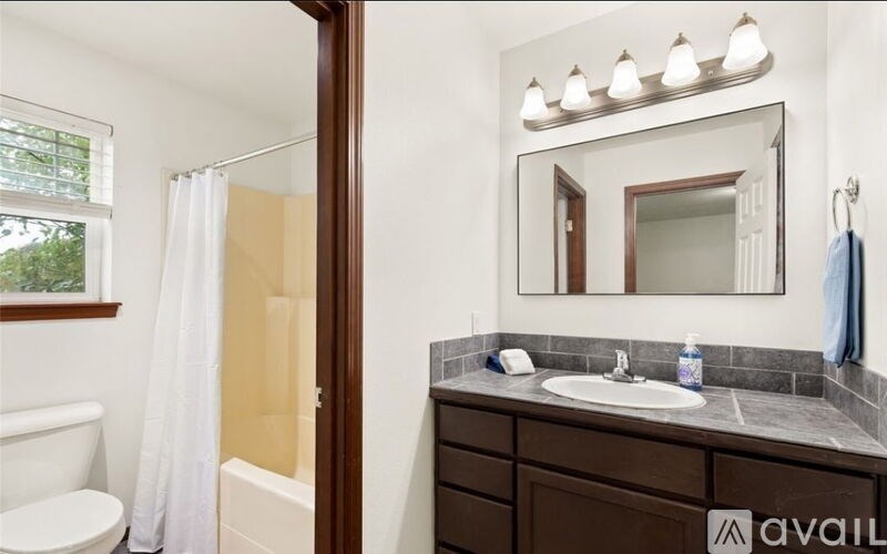 A bathroom with a white toilet, a sink, a mirror, and a shower.