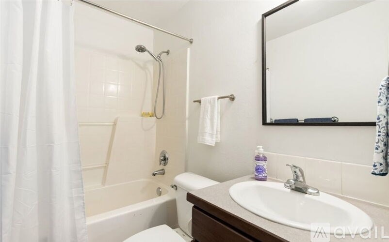 A white bathroom with a white toilet, a white sink, a white bathtub, and a white shower curtain.